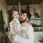 A joyful moment of a father holding his daughter in a cozy living room setting.