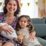 A happy mother with her children sitting on a sofa, enjoying family time indoors.